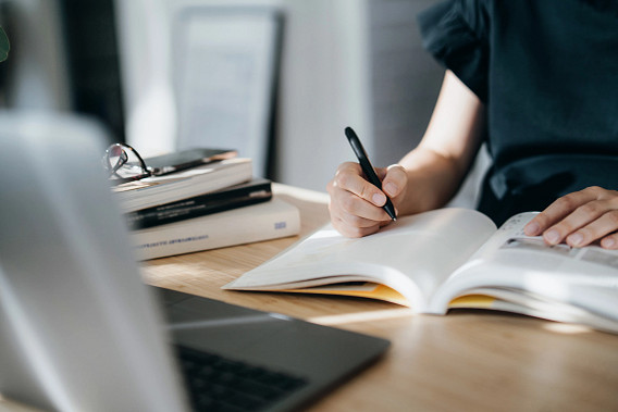 focused young Asian woman reading book and making notes at home, concentrates on her studies. Further education, continuous learning concept